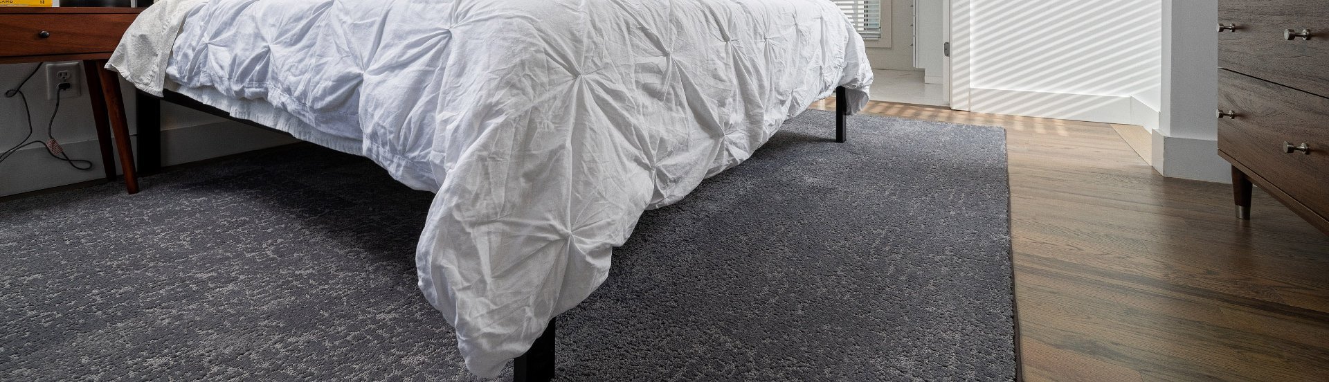 white bed on gray rug from The Carpet and Drapery Shoppe in Escanaba, MI