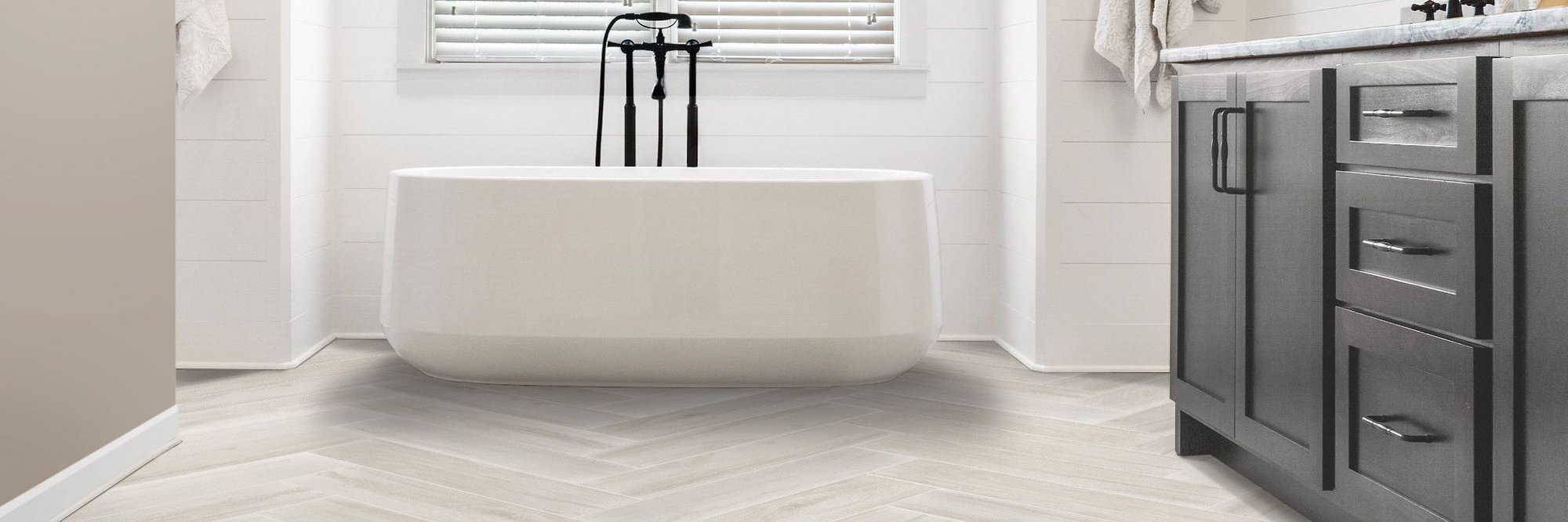 white bathtub and gray cabinet in bathroom with with tile from The Carpet and Drapery Shoppe in Escanaba, MI